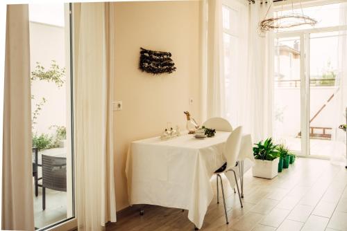 a white table with white chairs in a room with windows at Veronika Home Tbilisi in Tbilisi City