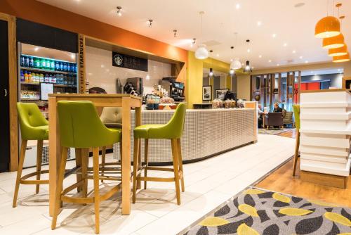 a bar in a restaurant with green stools at Holiday Inn Rotherham-Sheffield M1,Jct.33 by IHG in Rotherham
