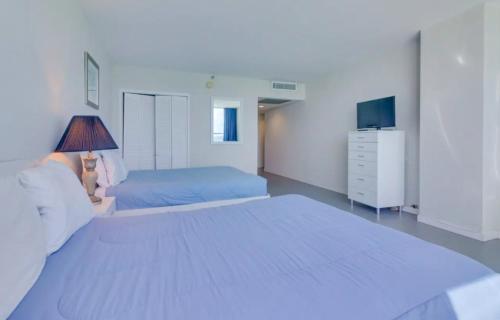 a large white bedroom with two beds and a dresser at Castle 835 Oceanview studio on beach with pool, gym, bars, and FREE Parking in Miami Beach