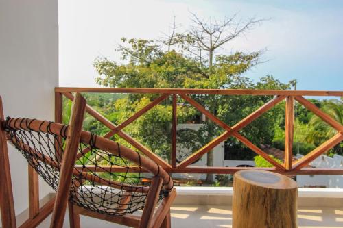 a rocking chair on a balcony with a tree stump at Casa de Olas Boutique Hotel in Puerto Escondido