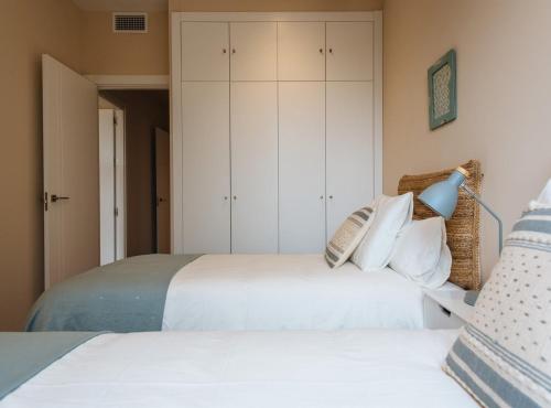 two beds in a bedroom with white cabinets at San Martín Suites Apartments in Seville