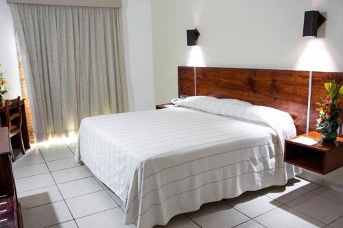 a bedroom with a large bed with a wooden headboard at Hotel Castillo Huatulco & Beach Club in Santa Cruz Huatulco
