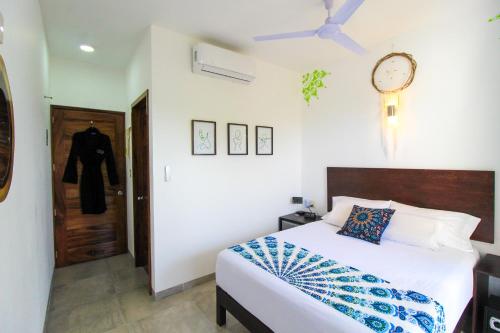 a bedroom with a bed and a clock on the wall at Casa de Olas Boutique Hotel in Puerto Escondido