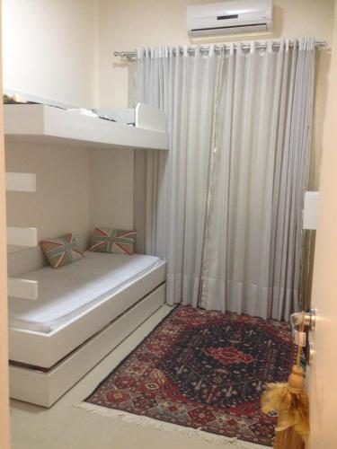1 dormitorio con 1 cama con cortina y alfombra en Apartamento Terra Nova Mariscal, en Bombinhas