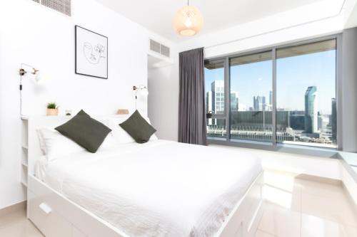 a bedroom with a white bed and a large window at Quintessential Quarters: 29th Fl Views - Walk to Opera, Mall and Burj Khalifa in Dubai