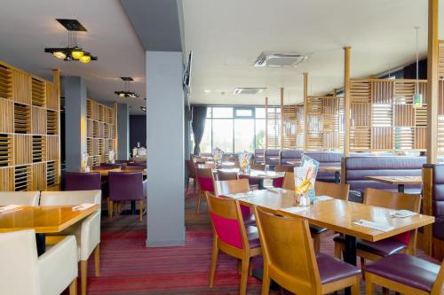 a dining room with wooden tables and chairs at Holiday Inn Aberdeen West by IHG in Westhill 