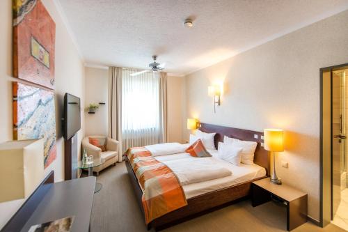 a hotel room with a bed and a chair at Hotel Stein - Schiller's Manufaktur in Koblenz