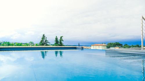 uma grande piscina de água azul com edifícios ao fundo em Solho Hotel em Bardolino