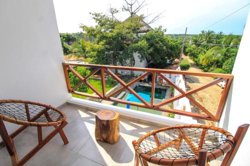 a balcony with two chairs and a view of a pool at Casa de Olas Boutique Hotel in Puerto Escondido