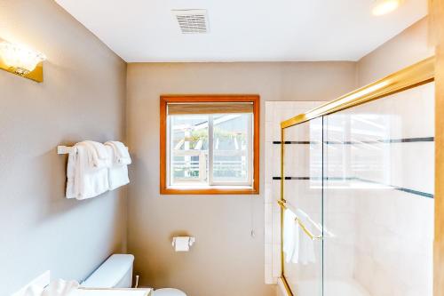 a bathroom with a shower and a toilet and a window at Seaside Serenade in Seaside