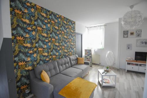 a living room with a couch and a floral wall at Appartement "le Terminus " Gare-Cosy-Wifi 6 Personnes in Saint-Quentin