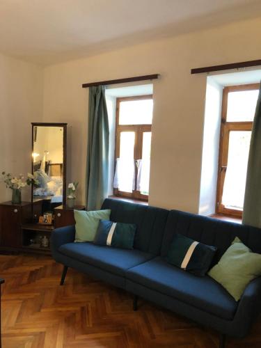 a blue couch in a living room with windows at Nagymama Vendégháza in Telkibánya