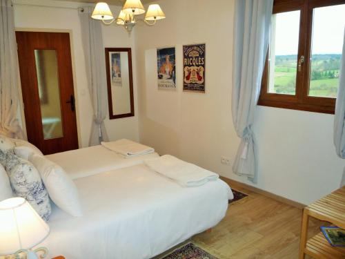a white bedroom with two beds and a window at Chez Edèll in Monpazier