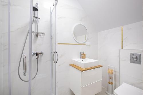 a white bathroom with a shower and a sink at Rezydencja nad rzeką in Łeba