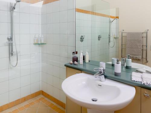a white bathroom with a sink and a shower at Windhover Suites in Tasman
