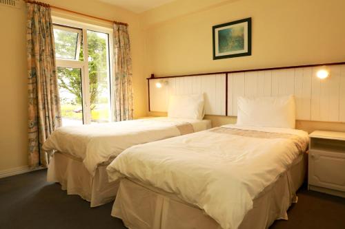 two beds in a hotel room with a window at Arus Grattan in Galway