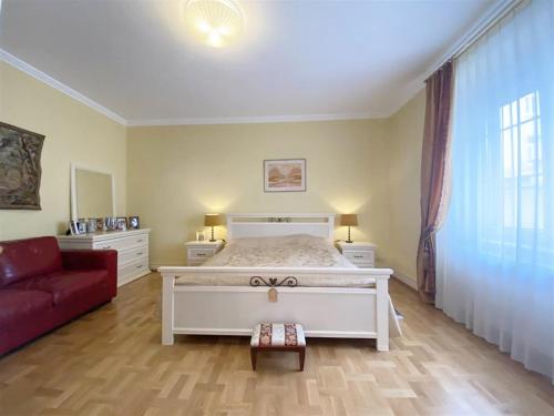 a bedroom with a white bed and a red couch at Baden-BadenSpaApartment in Baden-Baden