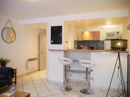 une cuisine avec un comptoir et des tabourets dans une pièce dans l'établissement Les Cosy de Nancy - Le repère du roi stanislas 4étoiles, à Nancy