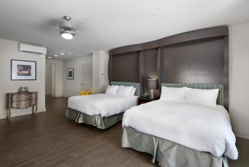 a hotel room with two beds with white sheets at White House Hotel in Biloxi