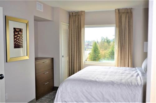 a bedroom with a bed and a large window at Staybridge Suites - Orenco Station by IHG in Hillsboro