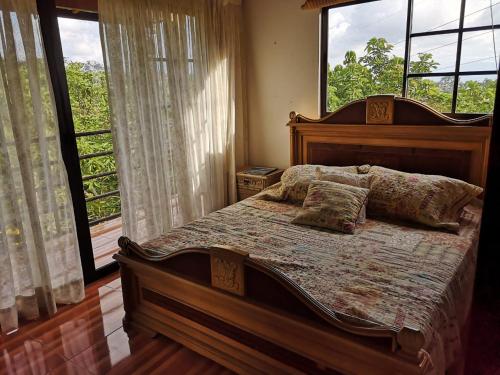 1 dormitorio con cama de madera con almohadas y ventana en Casa Mesa de Ruitoque, en Piedecuesta