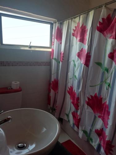 a bathroom with a sink and a shower curtain with flowers at CASA PRADA de Ruitoque in Piedecuesta