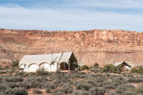 a white building with a roof in the desert at Under Canvas Moab in Moab