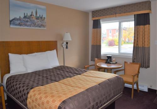 une chambre d'hôtel avec un lit, une table et une fenêtre dans l'établissement Knights Inn Arnprior, à Arnprior