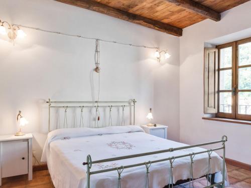 Un dormitorio con una cama con paredes blancas y techos de madera. en Flat with heated hot tub and shared pool, en Casola in Lunigiana