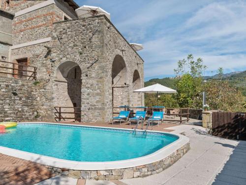 a pool in front of a stone building with chairs and an umbrella at Relaxing Tuscan Home with WiFi in Casola in Lunigiana