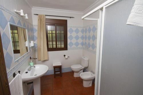 a bathroom with a white toilet and a sink at Casas el Albarracín in El Bosque