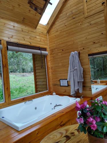 a large bath tub in a wooden room with a window at Chalés Estância Cachoeira do Avencal in Urubici