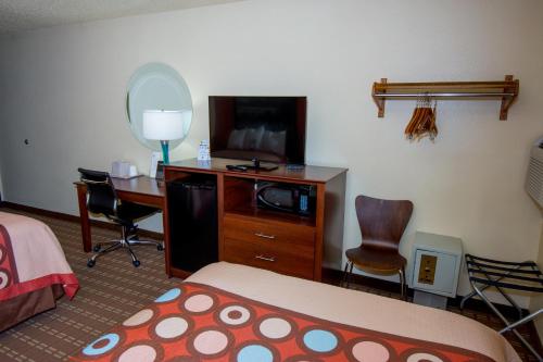 a hotel room with a bed a desk and a television at Super 8 by Wyndham Altoona in Altoona