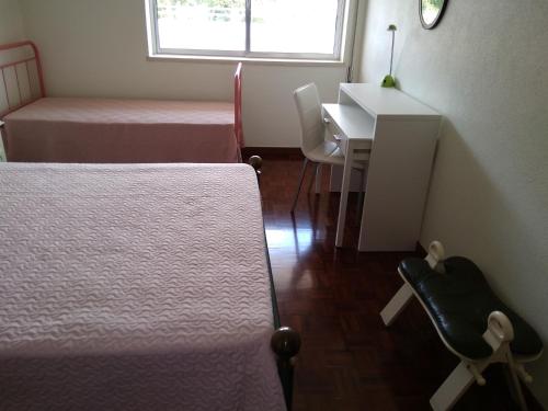 a bedroom with two beds and a desk and a table at O Terraço da Ribeira in Sertã