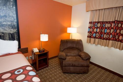 a hotel room with a chair and a bed at Super 8 by Wyndham Altoona in Altoona