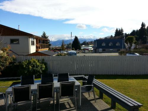 a table and chairs in a yard with a fence at Mountain View Backpackers in Wanaka