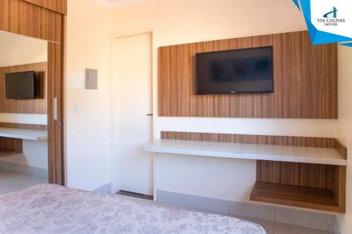 1 dormitorio con TV en la pared en Via Caldas L'acqua I, en Caldas Novas