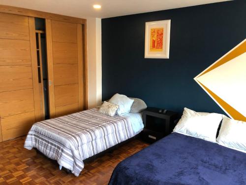 a bedroom with two beds and a blue wall at Caravansaro Vazquez de Mella 347 Polanco in Mexico City