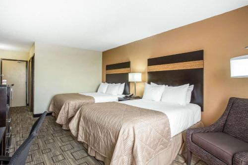 a hotel room with two beds and a chair at Clarion Hotel Fort Mill Near Amusement Park in Fort Mill
