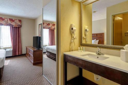 a hotel room with a sink and a mirror at Quality Suites in San Antonio