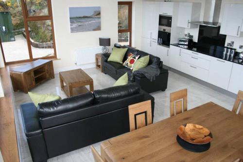 sala de estar con sofá de cuero negro y mesa en The Salthouse Lodges, en Ballycastle
