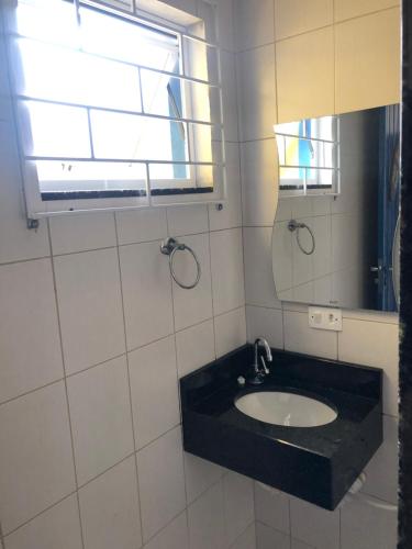 uma casa de banho com um lavatório e um espelho em PÉ NA AREIA apartamento térreo em Itapoá