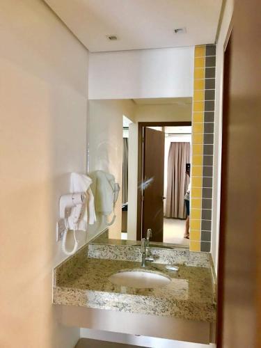 a bathroom with a sink and a mirror at Hospedagem Olímpia -SP in Olímpia