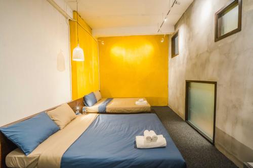 Habitación con 2 camas y pared amarilla. en The Garden Hotel & Apartment en Da Nang