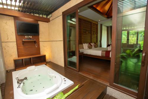 a bathroom with a tub in a room with a bedroom at Railay Village Resort-SHA Extra Plus in Railay Beach
