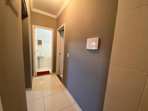 a hallway of a bathroom with a toilet and a sink at Green House Apartamentos in Ubá