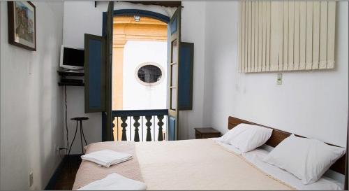 a bedroom with a bed and a window with a window at Pousada do Largo in Ouro Preto