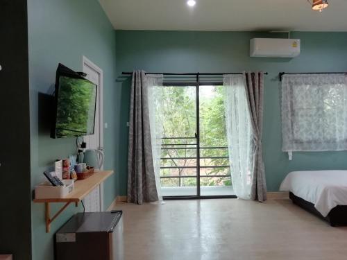 a bedroom with a bed and a large window at Morinaka Craftfe & Poshtel in Ban Na Muang