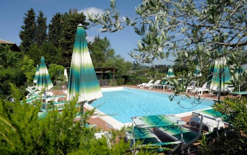 a swimming pool with umbrellas and lounge chairs next to it at Hotel Villa Belvedere in San Gimignano
