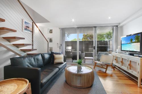 a living room with a black leather couch and a television at 5 Knots Metung in Metung